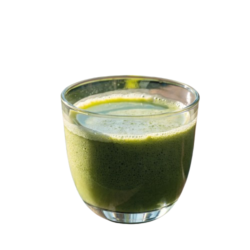 A glass of frothy green matcha on a wooden table outdoors, with soft sunlight and blurred greenery in the background.